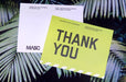 Custom 14pt uncoated matte postcards with white and bright yellow MASC Thank You card designs against a palm leaf background