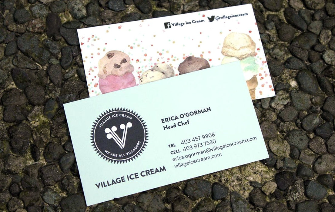 Custom 14pt uncoated business cards featuring watercolor ice cream illustrations for Village Ice Cream on a dark stone background