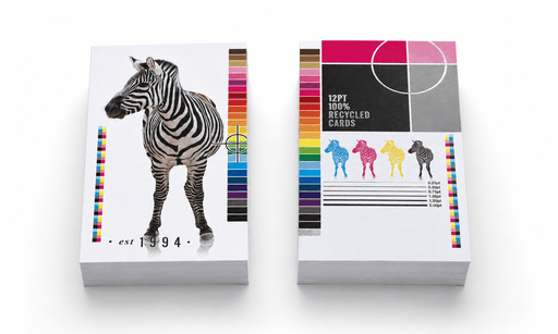 Stacks of custom-printed 100% recycled 12pt uncoated postcards for Clubcard Printing displaying a photorealistic zebra, four colorful zebra icons, and print calibration bars against a clean white background.
