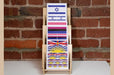 Front view of a 3-tier birch wood slim card display rack filled with flag sticker sheets made in the USA at Clubcard Printing in Palm Springs