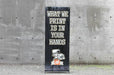 24 by 60 inch portable X-frame banner stand displayed outdoors against a concrete wall background
