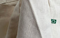 Close-up texture of natural eco-friendly recycled cotton canvas tote bag fabric with green recycling symbol tag