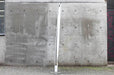 Side view of a white retractable banner stand set up outdoors against a concrete wall